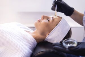 Day spa esthetician applies chemical peel to client's face.