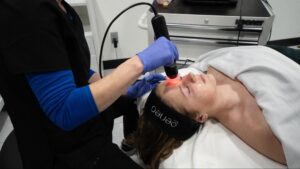 A professional aesthetician applying a soothing mask during an acne facial session in Fargo ND