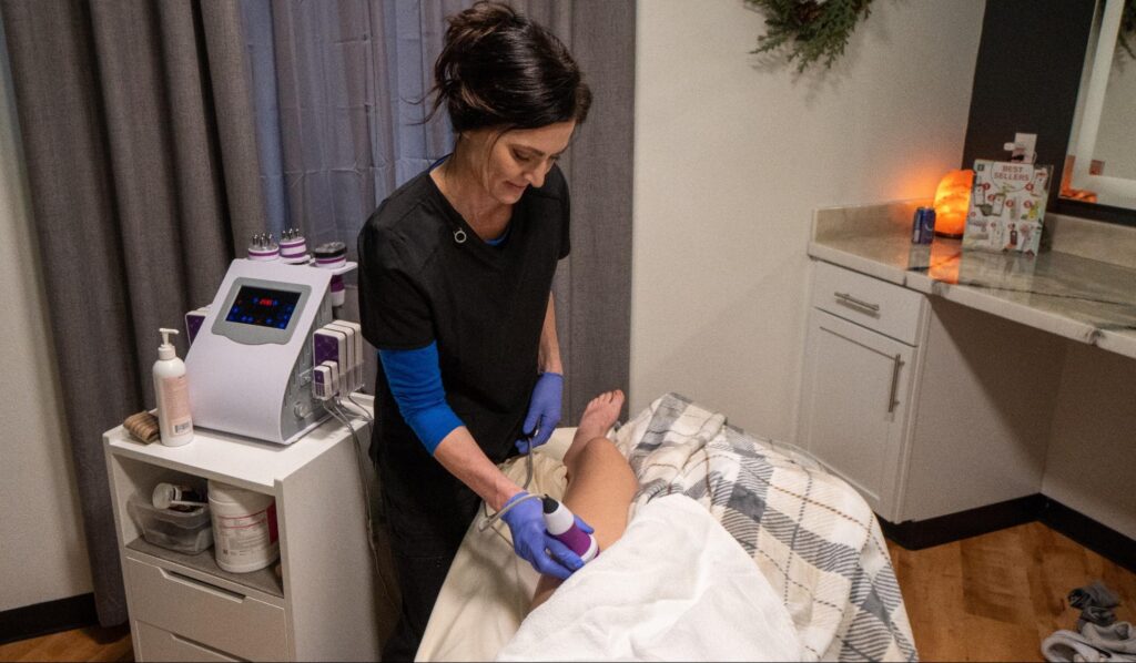 Aesthetician performing a non-invasive body sculpting procedure on a customer's leg