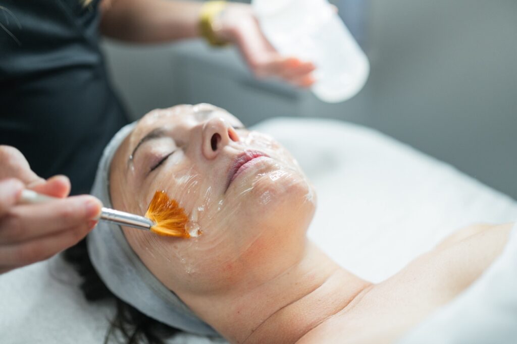 Esthetician applying a facial treatment on a client's face in a beauty spa during carboxy therapy