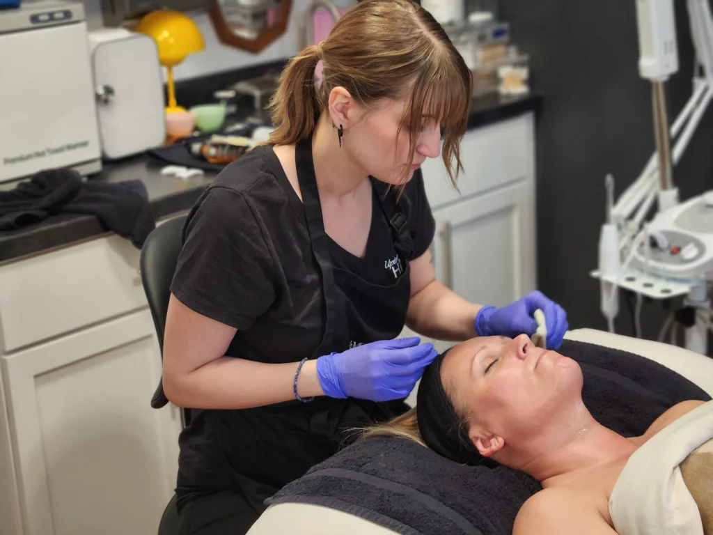 Uptown Haven esthetician giving a client a customized facial in a Fargo med spa treatment room