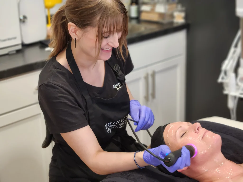 Uptown Haven esthetician performing a Glo2Facial treatment on a relaxed client in the Fargo treatment room