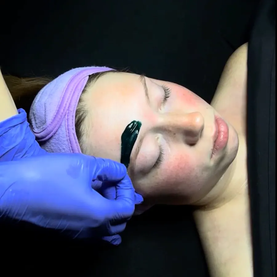 Esthetician waxing a client's brows